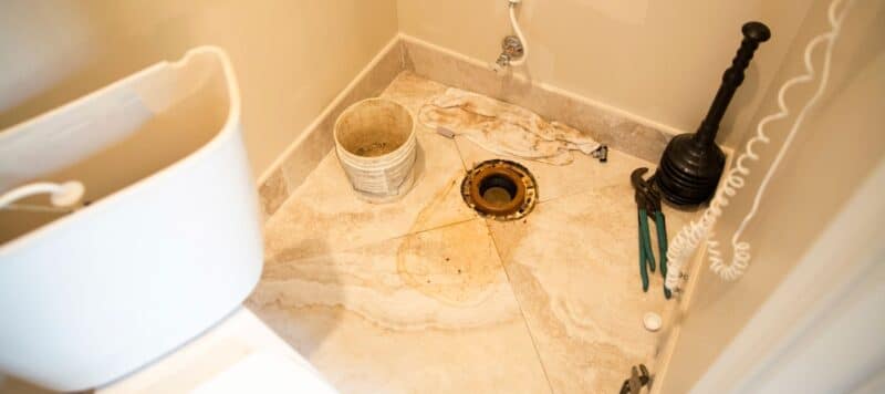 closeup of an area where a toilet should be sitting but is uninstalled to perform repairs due to a leak